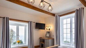 A bedroom with a large bed, a desk, a TV, and a view of the outdoors. - Bayview Terrace (Lynton)