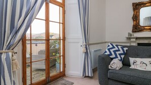 A living room with a sofa, a fireplace, and a view of a garden through a glass door. - Bayview Terrace (Lynton)