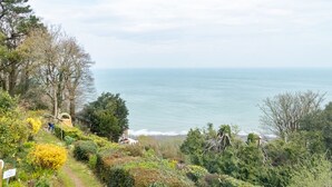 A coastal garden with a view of the sea, a 'NO EXIT' sign, and a pathway leading to a building. - Bayview Terrace (Lynton)