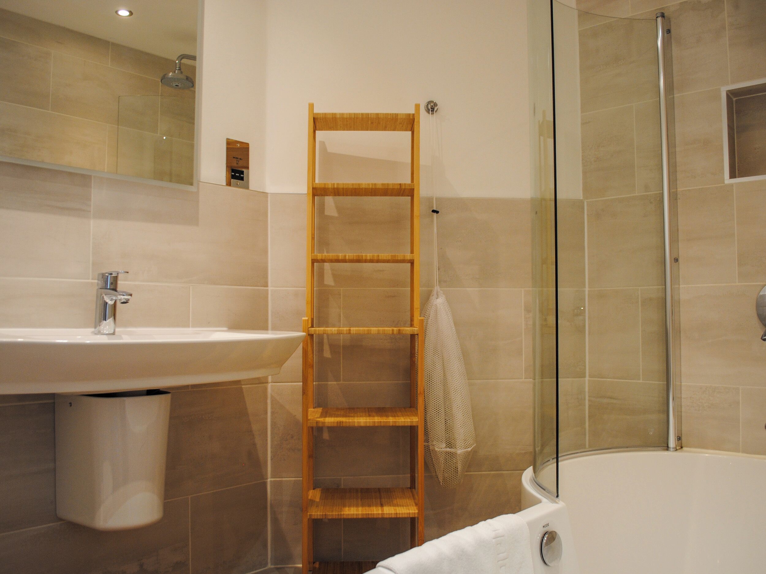 A bathroom with a wooden ladder, a sink, and a glass-enclosed shower.
