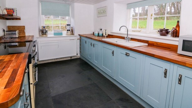 A kitchen with a wooden countertop, a sink, and cabinets. - Llwyncadfor Farm (Llandysul)
