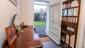 A wooden desk with a mirror, a framed picture, and a laptop. A door with a wooden frame and a small step is open, leading outside. - Llwyncadfor Farm (Llandysul)