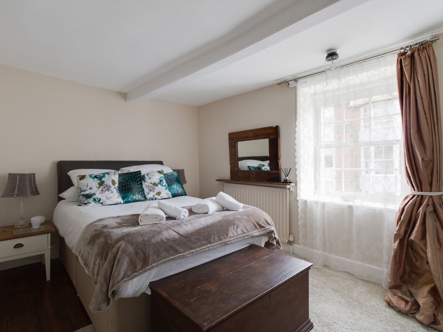 Une chambre à coucher comprenant un lit, une table de chevet, une lampe et une commode en bois.