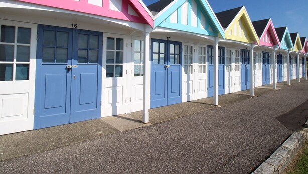 A row of colorful beach huts with numbered doors, each with a distinct color. - Fenders (Weymouth)