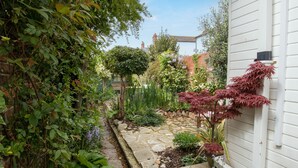 A garden with a stone pathway leading to a wooden bench. - Fenders (Weymouth)