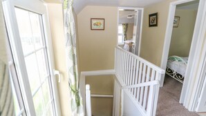 Un escalier avec des rampes blanches menant à une chambre à coucher où se trouve un lit.