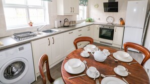 Une cuisine compacte équipée d’un lave-linge, d’une cuisinière et d’une table à manger pour quatre personnes.