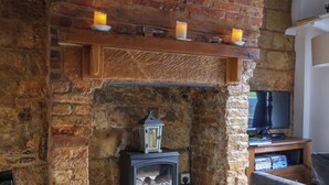 Una stanza accogliente con camino in pietra, un tavolino con candele, una televisione e un bollitore.