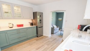 Una cocina moderna con armarios azul claro, un refrigerador de acero inoxidable y una encimera blanca.