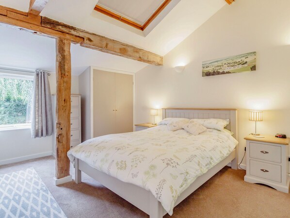 A bedroom with a bed, bedside tables, a wardrobe, and a painting on the wall. - The Hen House (Diss)