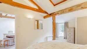 A bedroom with a bed, a dresser, a mirror, and a window. - The Hen House (Diss)