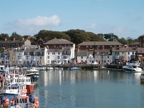 Un port de plaisance où sont amarrés des bateaux, entouré d’immeubles résidentiels à plusieurs étages.