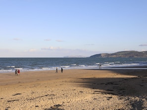 A wide sandy beach with people walking along the shore.