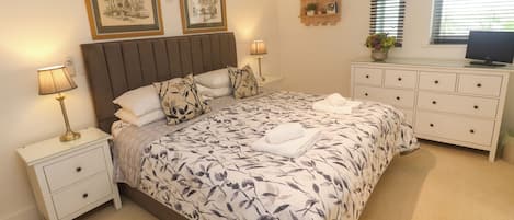 A bedroom with a bed, nightstands, a dresser, a ceiling fan, and framed pictures on the wall.