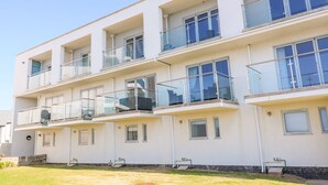 A multi-story residential building with balconies, large windows, and a flat roof. - Ocean Seven (Newquay)