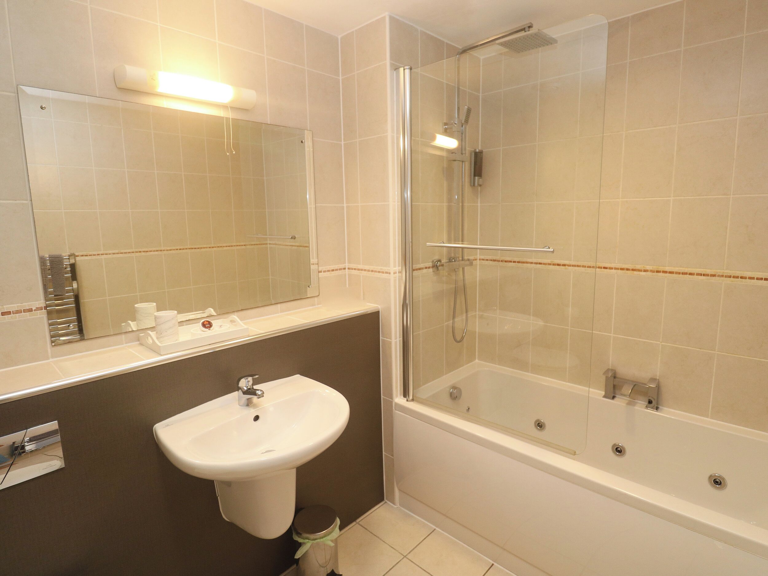 A bathroom with a sink, mirror, and a glass-enclosed shower area.