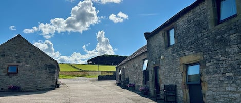 A stone building with a gravel driveway, a wooden fence, and flower beds.