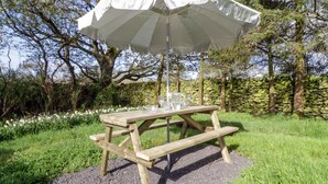 A wooden picnic table with a white umbrella and a stone wall in the background. - 5 Ceirnioge Cottages (Betws-Y-Coed)