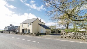 A two-story building with a stone facade, a sloped roof, and a gated driveway. - 5 Ceirnioge Cottages (Betws-Y-Coed)