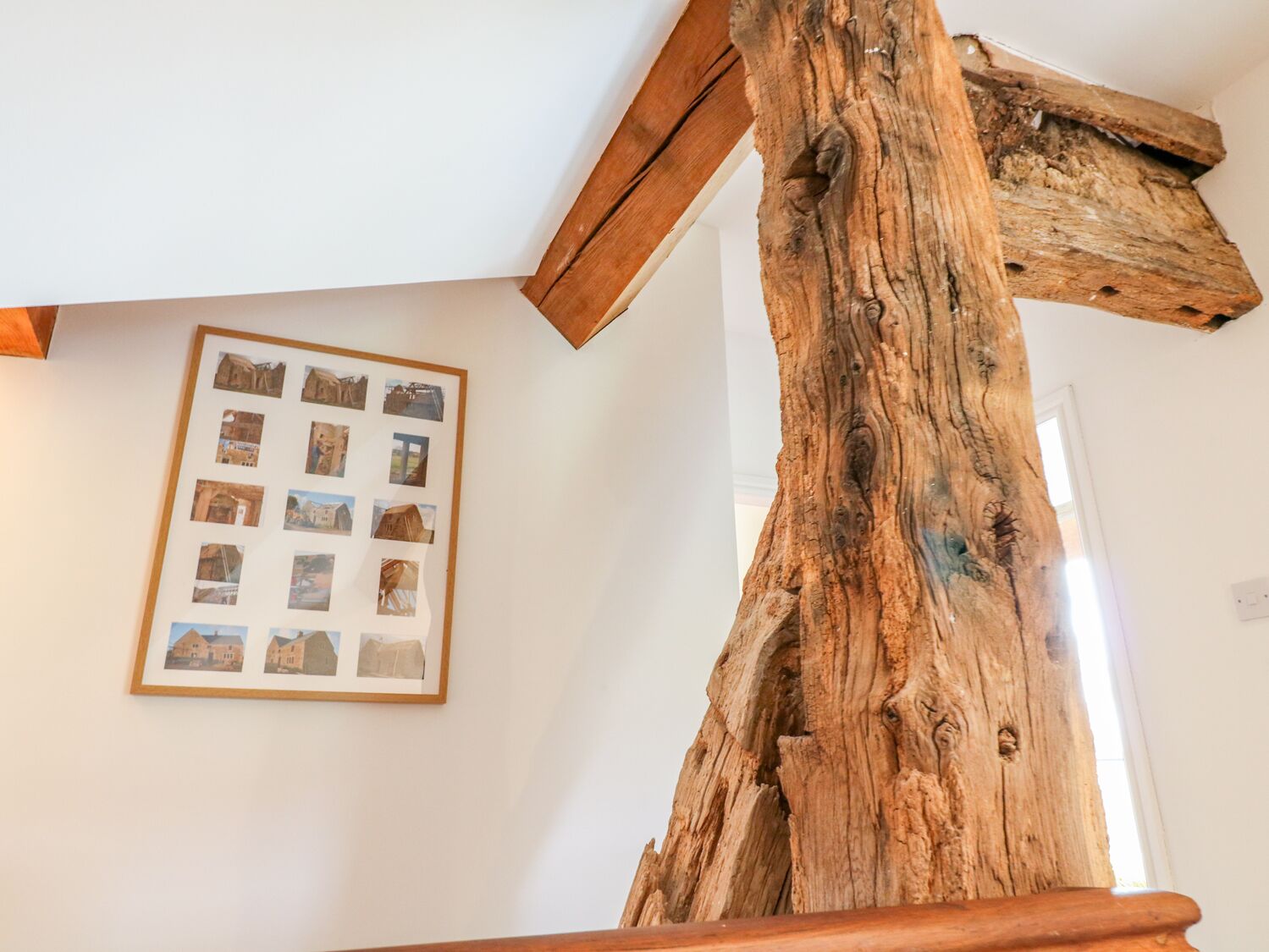 Estructura de vigas de madera en una habitación con una fotografía enmarcada de edificios en la pared.