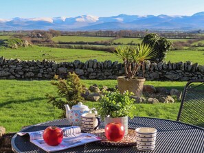 A table set outdoors with a view of a green field and mountains in the background.