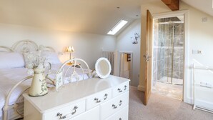 Une chambre à coucher comprenant un lit, une commode, une coiffeuse et un espace douche.