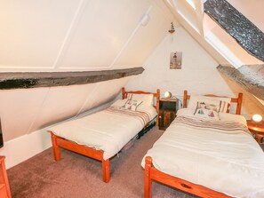 Ein kleines, gemütliches Schlafzimmer im Dachgeschoss mit zwei hölzernen Betten, einer geneigten Decke und rustikalem Charme.