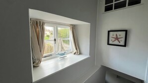 Una habitación con ventana, una decoración de estrella de mar y un pequeño estante.