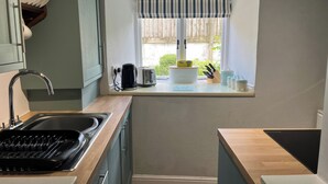 Una cocina compacta con ventana, tostadora, hervidor y pileta.