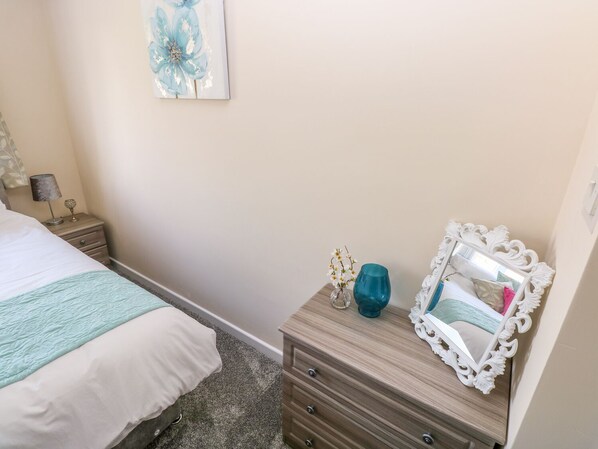 A bedroom with a bed, a nightstand, a dresser, a mirror, and a wall art piece.