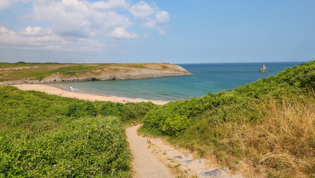 A coastal path leading to a beach with a view of the sea and a rocky outcrop in the distance. - Cranford Cottage (Pembroke)