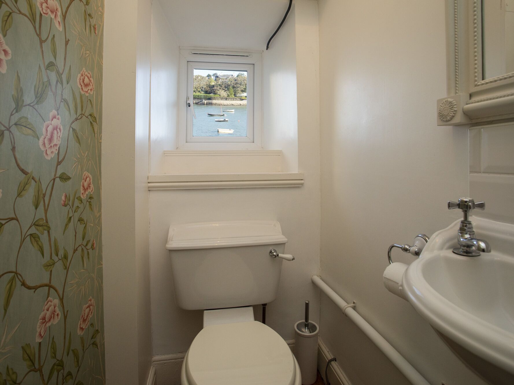 A small bathroom with a toilet, a window, and a sink.