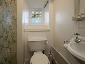 Une petite salle de bain avec des toilettes, une fenêtre et un lavabo.