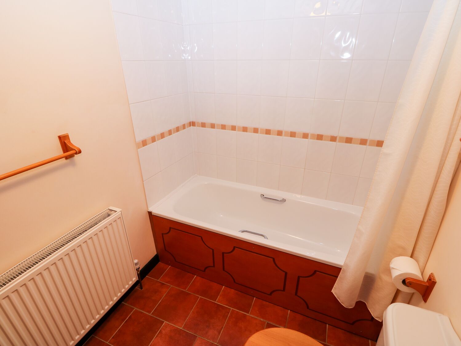 Un baño con bañera, toallero, inodoro y radiador.