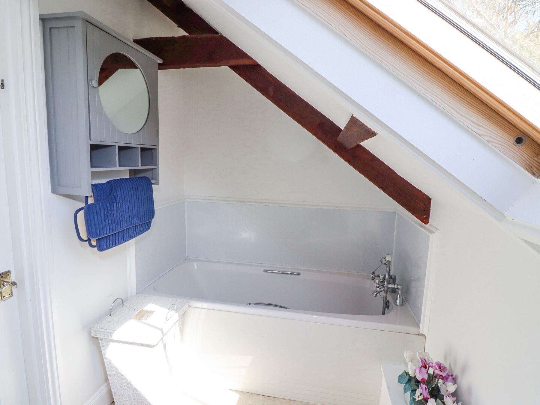 A bathroom with a bathtub, a mirror, and a towel rack.