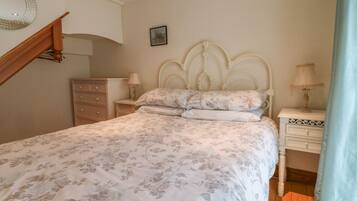 Un dormitorio con cama, cómoda, mesitas de noche y espejo.
