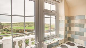 A kitchen with a view of rolling hills, a white stove, and a window with a view of the outdoors. - The Doves (Bridport)