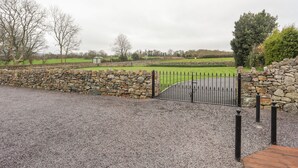 A stone wall with a metal gate leading to a gravel path. - Plas Cefn Mawr (Llanfairpwllgwyngyll)