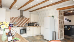 A kitchen with wooden beams, a white refrigerator, a microwave, and a stove. - Plas Cefn Mawr (Llanfairpwllgwyngyll)