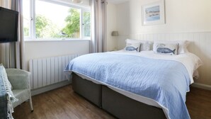 A bedroom with a bed, a chair, a window, and a television. - Keelyn (Newquay)