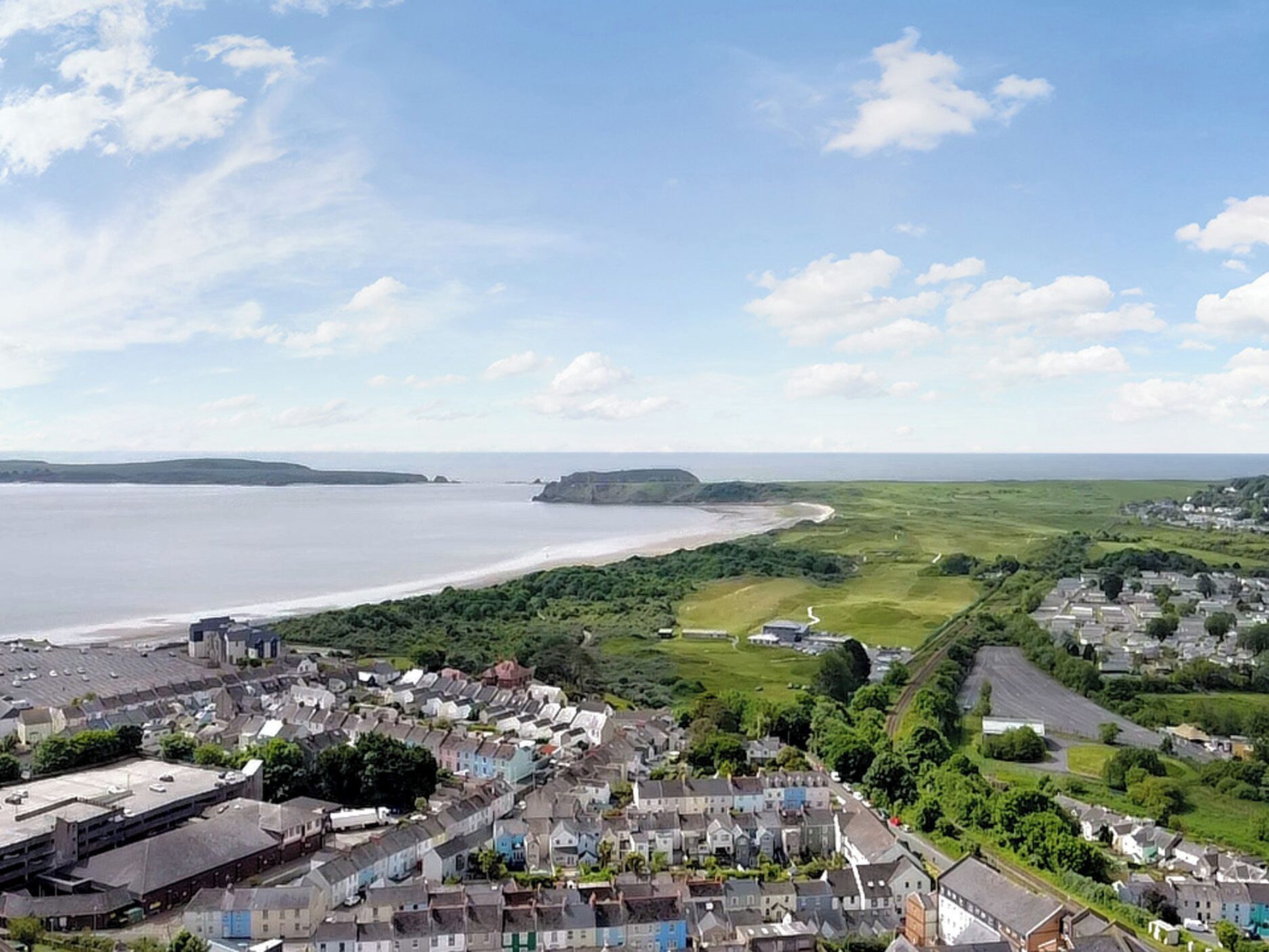 A coastal town with residential buildings, a beach, and a cliff.