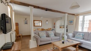 A cozy living room with a sofa, a coffee table, and a TV. There is a wooden cabinet and a chair. - George's House (Weymouth)