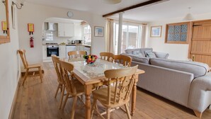 A cozy living space with a dining area, a sofa, and a kitchen in the background. - George's House (Weymouth)