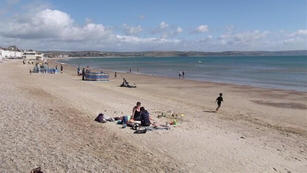 A beach with people relaxing and some tents set up. - George's House (Weymouth)
