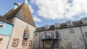 A courtyard with a staircase leading to a second floor, surrounded by buildings with "No Parking" signs. - George's House (Weymouth)