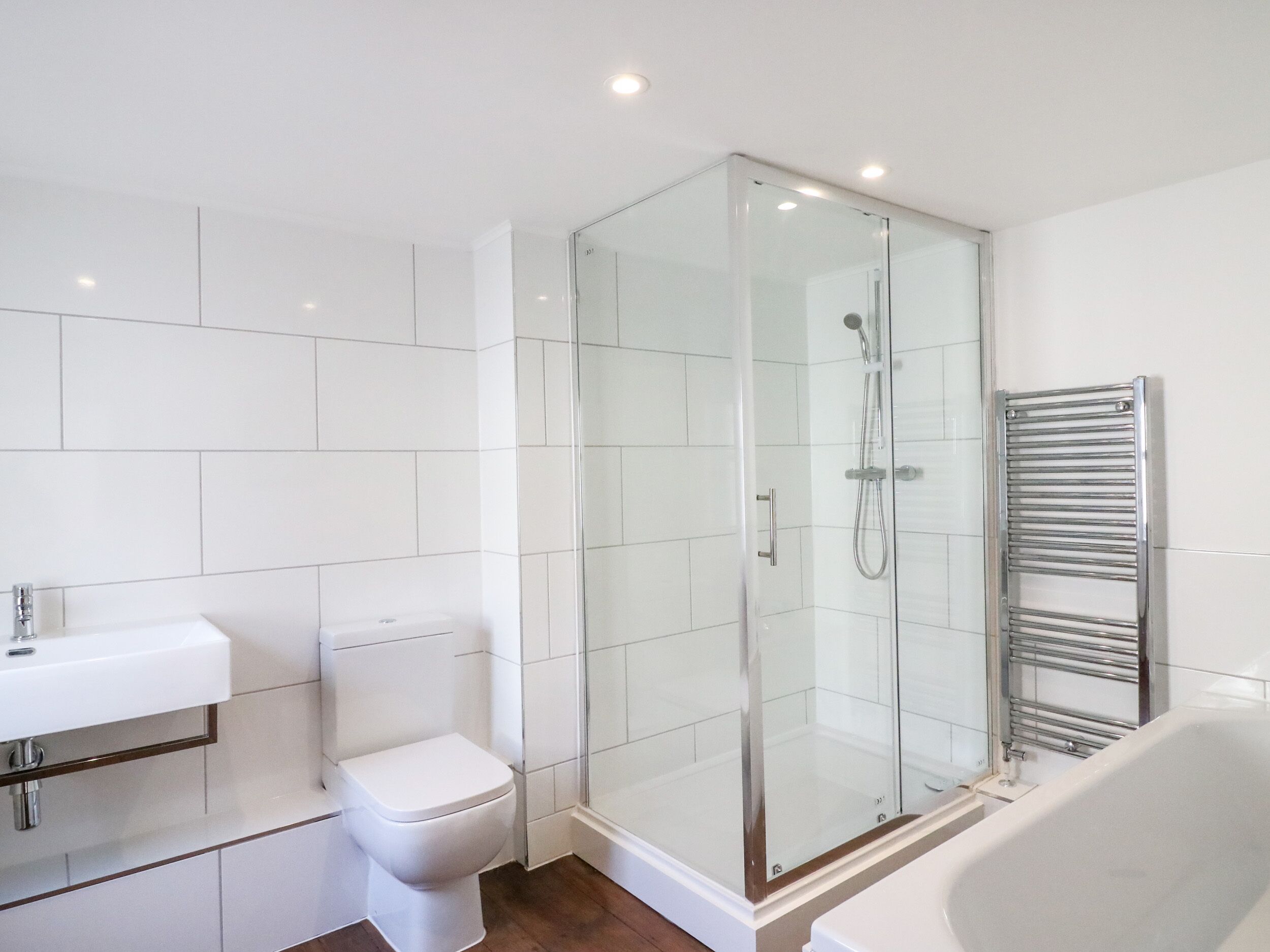 Un baño moderno con ducha envuelta en vidrio, inodoro blanco y bañera.
