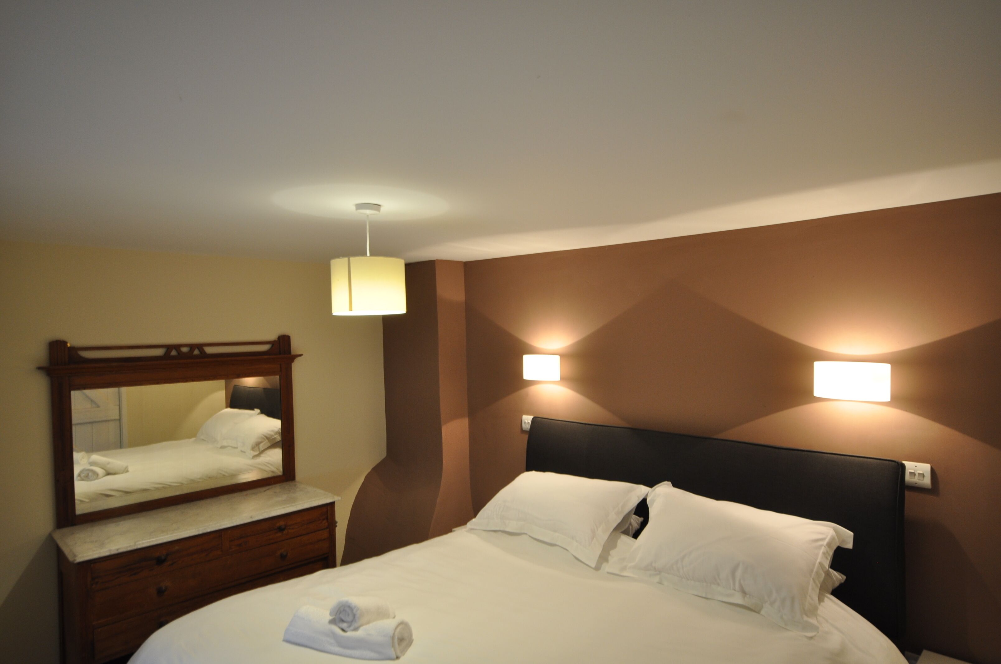 Een hotelkamer met een bed, een kaptafel, een spiegel en twee wandlampen.