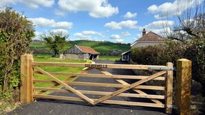 A wooden gate with the name 'Culverwells' on it, leading to a rural area with houses and green fields. - Culverwells (Axminster)