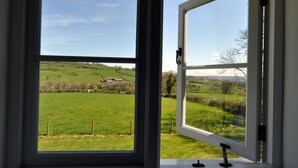 A window with a view of a green field and a distant building. - Culverwells (Axminster)