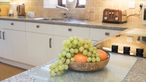 A kitchen with a wooden bowl containing grapes and an orange on the counter.